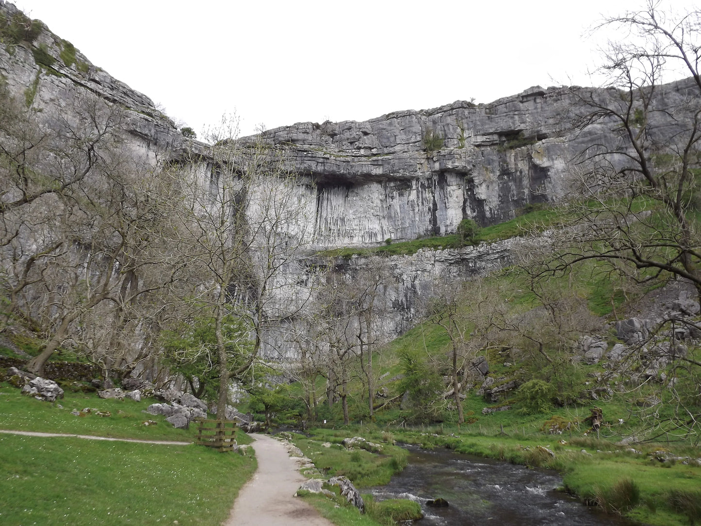 Yorkshire landscape with limestone cliffs, bare trees, green grass, walking path, and small river