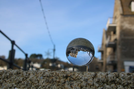 Crystal ball on stone wall reflecting inverted coastal buildings and blue sky