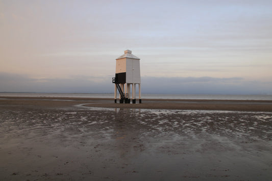 Burnham-on-Sea wooden lighthouse on sandy beach at sunrise with calm sea and cloudy sky