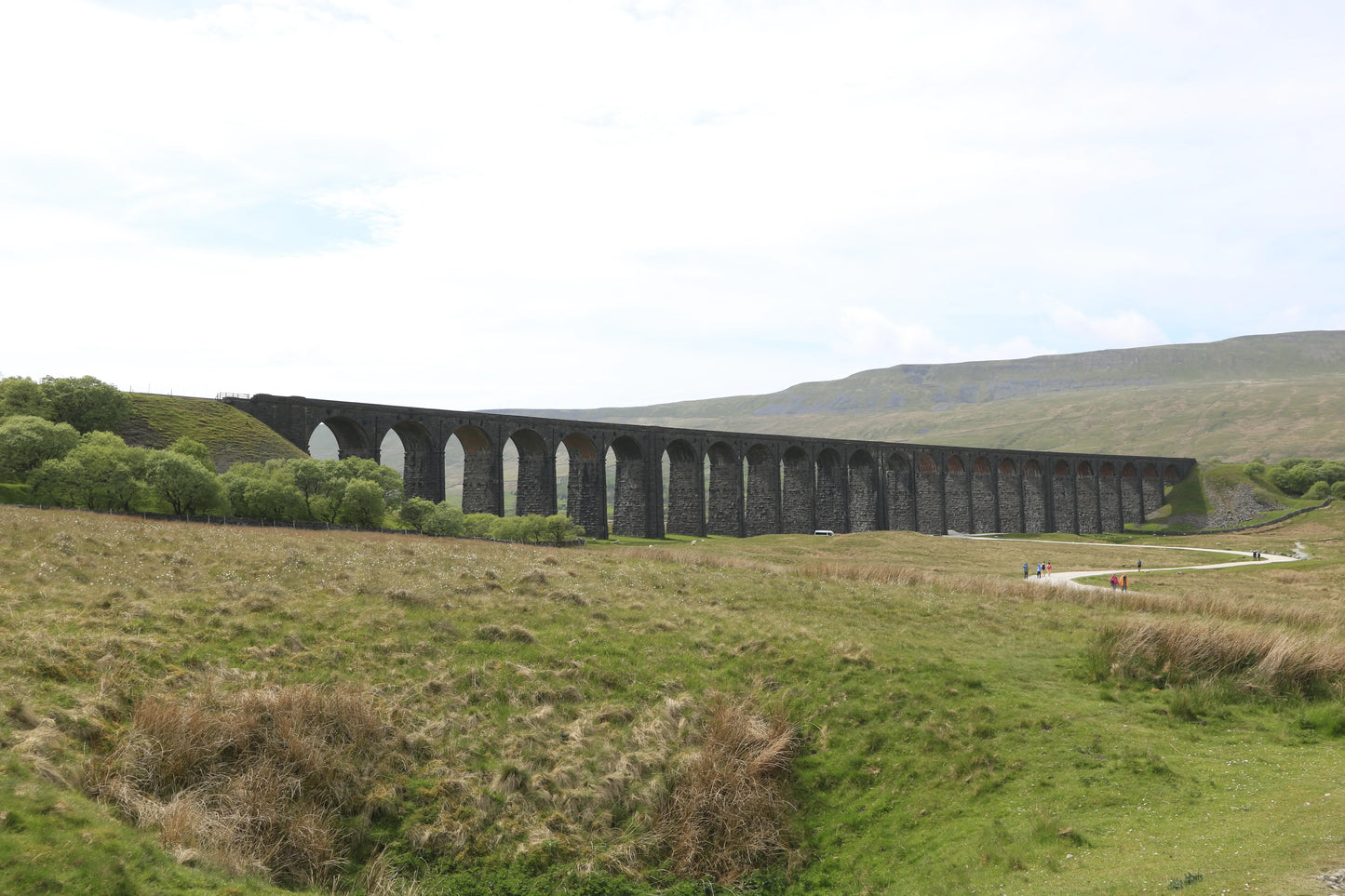 Ribblehead Viaduct in Yorkshire, historic stone railway bridge over green moorland with hills in background