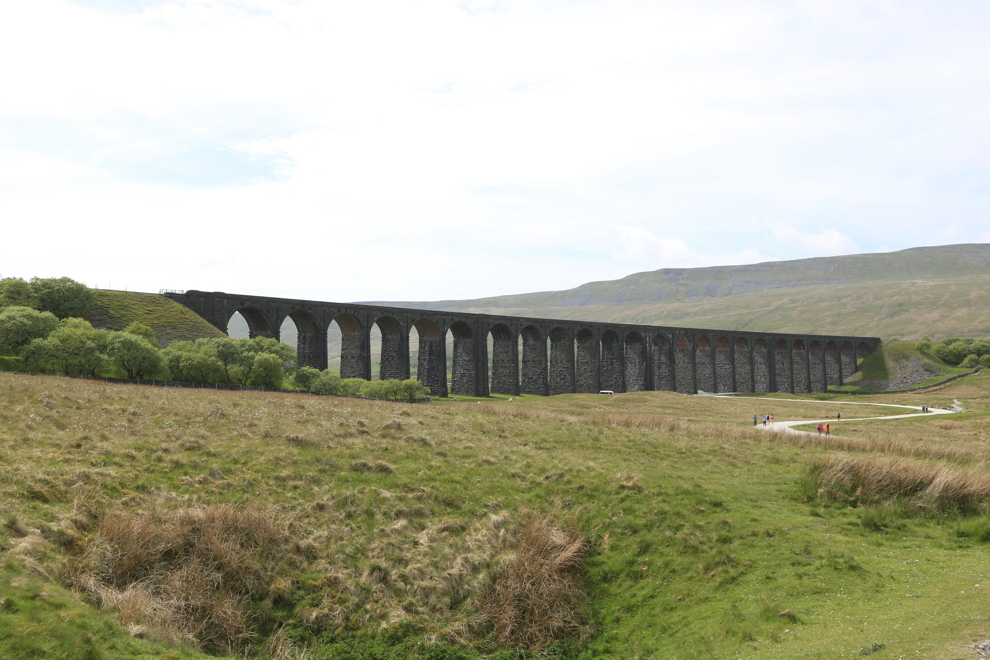 Ribblehead Viaduct in Yorkshire, historic stone railway bridge over green moorland with hills in background