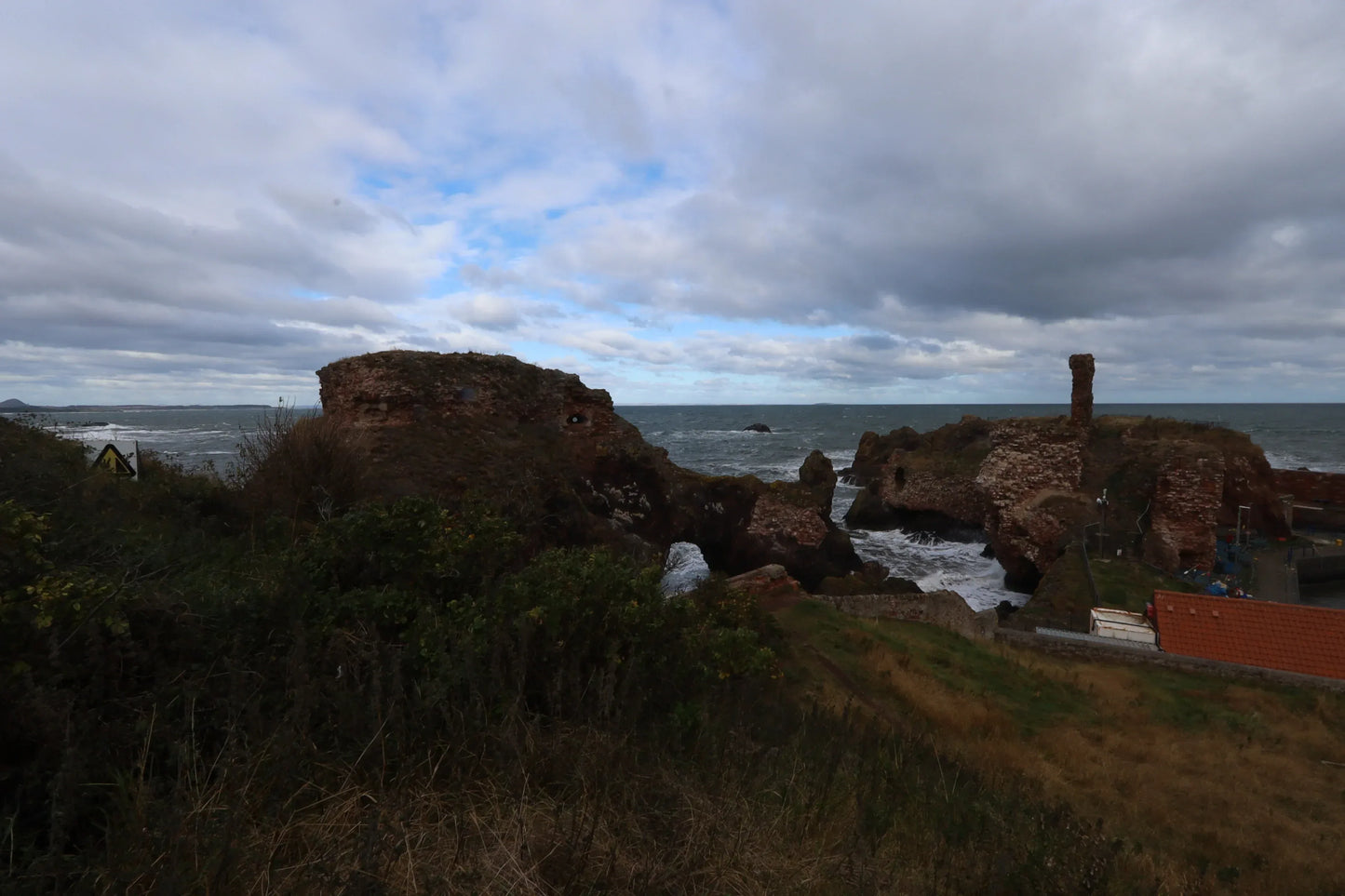 Northumberland Dunbar Coast ruins with rocky shoreline under cloudy UK sky