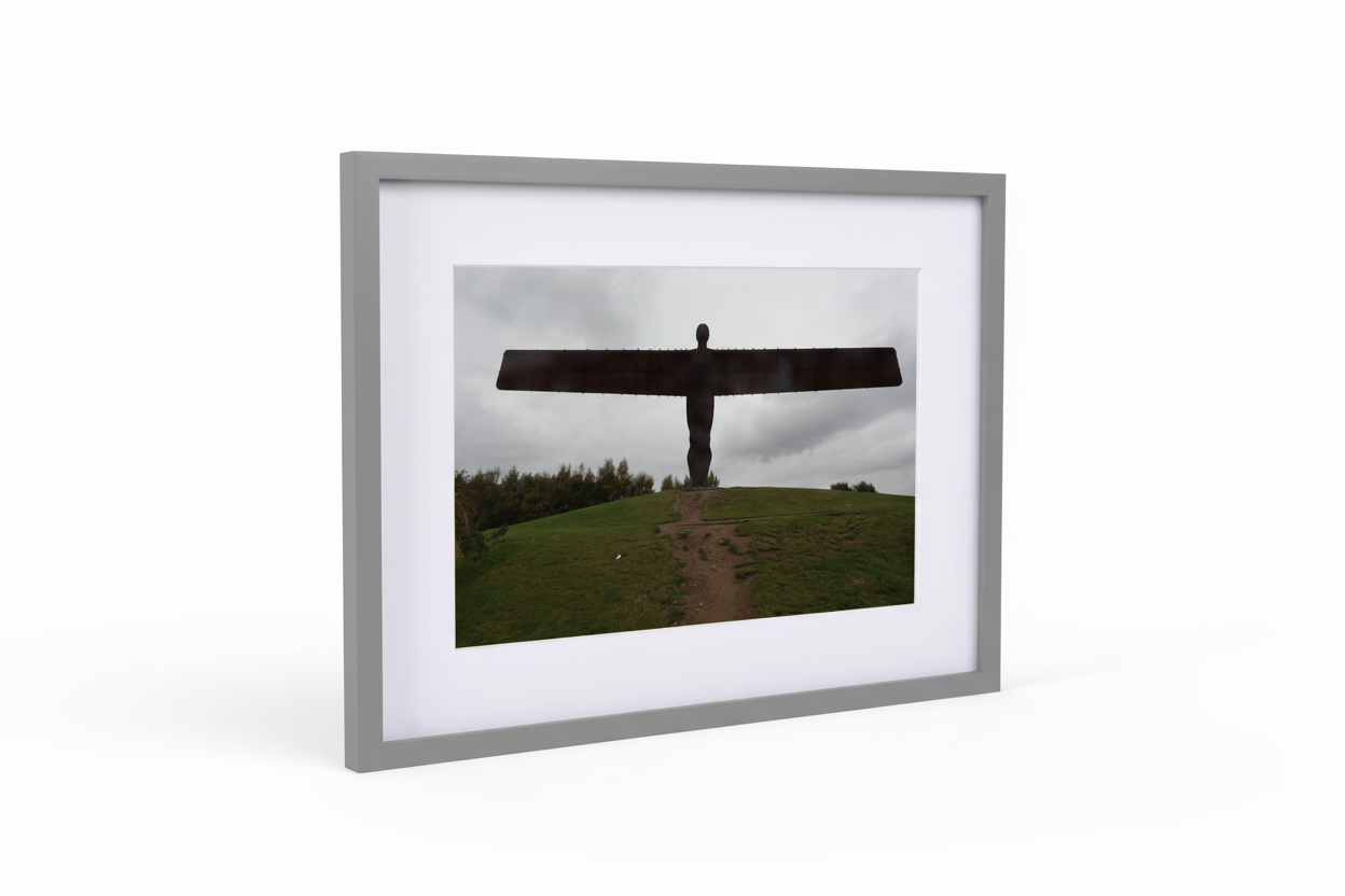 Framed photographic print of the Angel of the North sculpture on a grassy hill under a cloudy sky