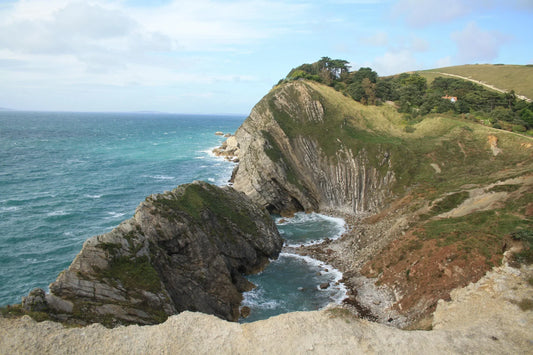 British coastal landscape with rugged cliffs and turquoise sea under partly cloudy sky